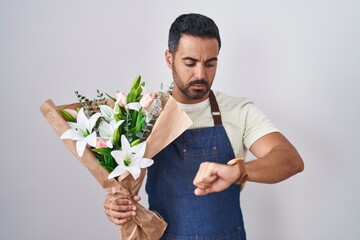 Poster - Hispanic man with beard working as florist checking the time on wrist watch, relaxed and confident