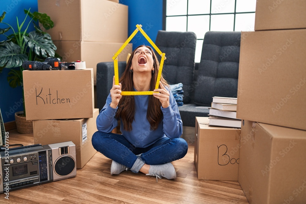 Young brunette woman sitting on the floor at new home angry and mad ...