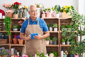 Canvas Print - Middle age grey-haired man florist smiling confident using touchpad at florist