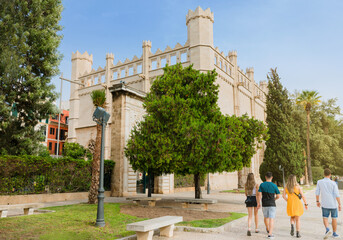 Grupo de jóvenes caminando por el Paseo Sagrera de Palma de Mallorca, junto a la Lonja, edificio medieval del gótico civil. Mallorca, Islas Baleares, españa.