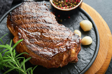 Steaks. Grilled New York Steak with spices rosemary and pepper on black marble board on gray background. Top view. Mock up.