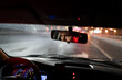 © DimaBerlin - Look of man is reflected in rear-view mirror traveling in car in evening hurries home after work. Speedometer with neon lights and eyes young guy working as driver or cabbie and enjoying city at night