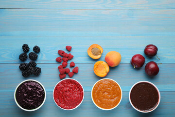 Different puree in bowls and fresh fruits on light blue wooden table, flat lay. Space for text