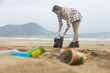 A woman cleans up trash from the beach. plastic environmental pollution