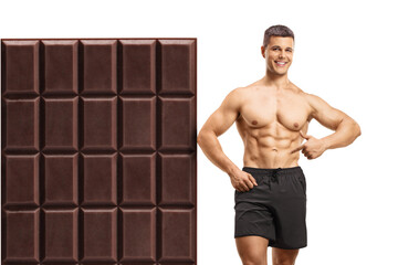 Canvas Print - Shirtless man leaning on a big chocolate and showing abdominal muscles