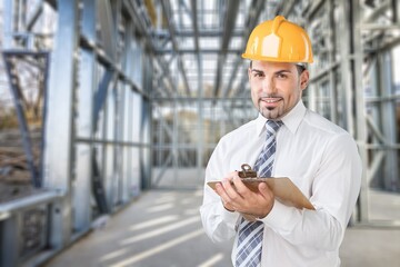 Wall Mural - Professional young man with a clipboard posing on construction site.