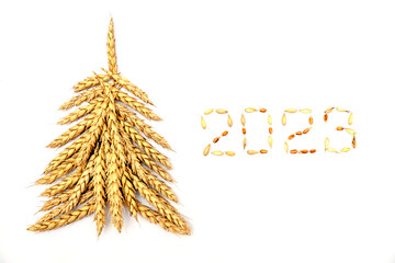 Wall Mural - Creative Christmas tree made of wheat ears.New year 2023 made of grains on a black background.Creative New Year's flat lay.