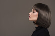 Portrait of a beautiful brunette woman with a short haircut on a gray background