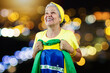 Senior Woman With Brazil Flag on Bokeh Background cheering for Brazil to be the champion