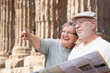 Happy Senior Adult Couple Tourists with Brochure Next To Ancient Column Ruins.