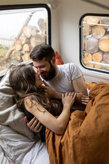 Wall Mural - Young beautiful loving couple travelling across country in the van. Millennial man and woman in a travel camper. Cozy atmosphere, vacations vibe