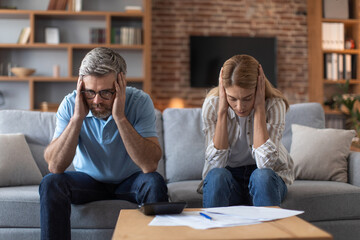 Wall Mural - Despaired sad middle aged european couple suffer from bills in living room interior