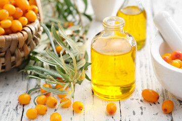 Wall Mural - Bottles of sea buckthorn essential oil, mortar and basket of sandthorn berries.