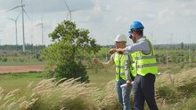 Three Asian Engineers Working In Wind Turbine Field. Men Worker Checking Plan For Construction On Wind Farms. Wind Turbine. Generate Electricity. Renewable Energy For Reduce Greenhouse Gas Emissions.
