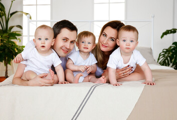 Portrait, large family, with triplets on the bed. Parents and small children. Medicine, eco