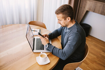 Wall Mural - a busy man sits at home and typing messages on the phone.