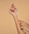 © vladimirfloyd - Close up cropped woman apply  hand perfect skin hand cream isolated on beige studio  background.