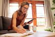© Nina Lawrenson/peopleimages.com - Phone, writing and senior woman planning retirement, taxes and budget on living room sofa of her house. Elderly person working on strategy for insurance in book with an email on mobile app with tech