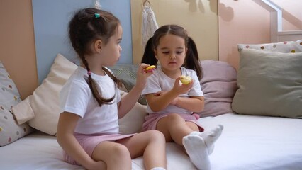 a little cute girl does not give a cake macaroon to her sister.