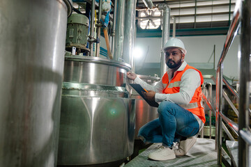 Wall Mural - Professional engineering man in protective safety uniform and white hardhat working with clipboard at factory.