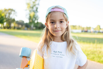 smiling kid skater with skateboard outdoor. Hipster girl with penny board. 