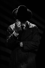 A Dark Silhouette Of A Man In A Coat And Hat In The Noir Style. A Dramatic Portrait In The Style Of Detective Films Of The 1950s And 60s. The Silhouette Of A Spy.