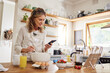 © Nina Lawrenson/peopleimages.com - Baking, website and phone with woman cooking food while reading online with blog, internet or app. Kitchen, network and breakfast with chef with web and search recipe for diet, nutrition or lunch
