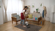 © PRPicturesProduction - full length asian housewife vacuuming the carpet with a hoover in a modern bright home living room interior while going through house cleaning routine