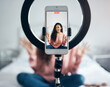 © Tashriq P/peopleimages.com - Live streaming, phone and black woman talking on video podcast in the bedroom of her house. Happy and excited girl or influencer speaking on the internet or social media with a mobile and ring light