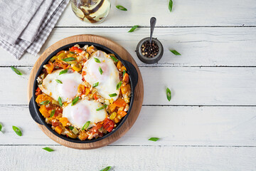 Wall Mural - Shakshouka in frying pan. Fried eggs with vegetables, tomato, pepper, pumpkin and onion. Top view