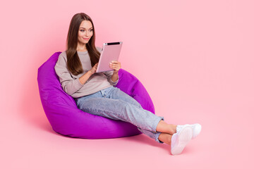 Wall Mural - Full size portrait of pretty girl sitting comfort bag use tablet isolated on pink color background