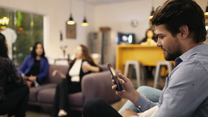 young man looking at smartphone device in resting room at workplace. person browsing internet social