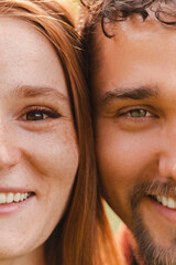 Wall Mural - Vertical cropped portrait of young beautiful couple looking at the camera and smiling, Half face crop.