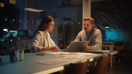 Leinwandbilder - Successful Young Small Business Owners Communicating at a Meeting in Office at Night. Beautiful Female and Handsome Male Discussing Corporate Agenda and Opportunities. Managers High Five Each Other.