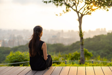 Wall Mural - Woman sit on the wooden bench and look at the sunset