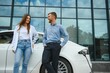 © Serhii - Happy young adult man and smiling woman charging electric car.