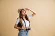 young attractive Asian woman traveler in casual clothes wearing straw hat with backpack and camera isolated on yellow background, Tourist girl having cheerful holiday trip concept
