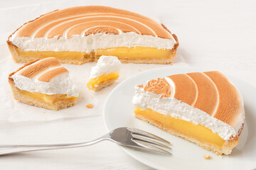 Poster - Cut up lemon tart with meringue topping next to a portion of lemon tart on plate with a fork.