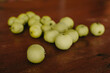 Green small garden apples on a wooden table.