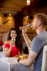 Wall Mural - Young couple having lunch with white wine in the restaurant