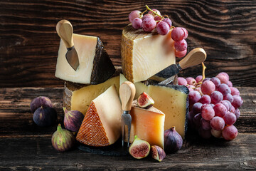 Wall Mural - Various kind of cheese, traditional pieces of french, italy and spanish manchego cheese with grapes and figs served on wooden table