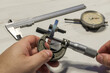 Manos de mecánico midiendo de espesores con micrómetro donde se aprecian además un calibre pie de rey y un reloj comparador