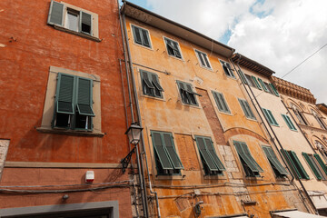 Wall Mural - Vintage facades of beautiful colored houses with green wooden shutters. Travel in the European city of Pisa, Italy