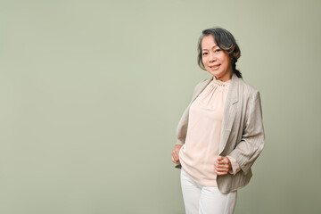 Gorgeous aged-asian businesswoman or female CEO in casual suit, isolated over green background