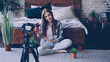 © silverkblack - Pretty young girl popular blogger is recording video about house flowers with camera sitting on floor near double bed in nice bedroom. Girl is talking and holding plant.