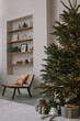 Stylish home interior with beautiful huge Christmas tree, gifts and decorations. Modern minimalistic apartment ready for winter holidays. Aesthetic Christmas background.