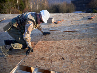 Canvas Print - Carpenter mounting wooden OSB board on rooftop of future cottage. Man worker building wooden frame house. Carpentry and construction concept.