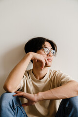 Asian man thinking and looking aside while sitting on floor at home