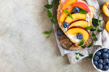 Wall Mural - Vegetarian croissant sandwiches with nectarine, soft or cream cheese, blueberries and honey on concrete background. Healthy breakfast or lunch.