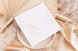 Square envelope on plate on dried palm leaf and beige silky fabric close up, mockup